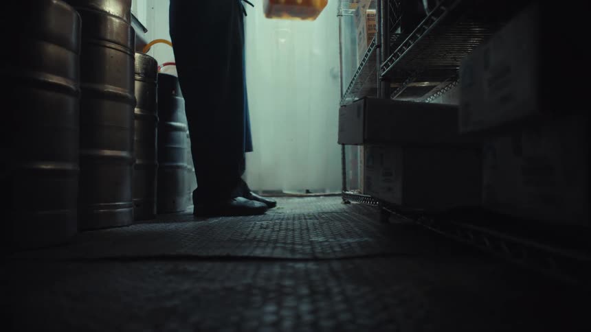 Low angle shot of a chef entering a restaurant's walk-in cooler to retrieve a container of food supplies