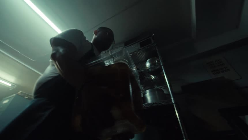 Low angle slow motion of a chef carrying a heavy container of pickled eggs through a restaurant storage room
