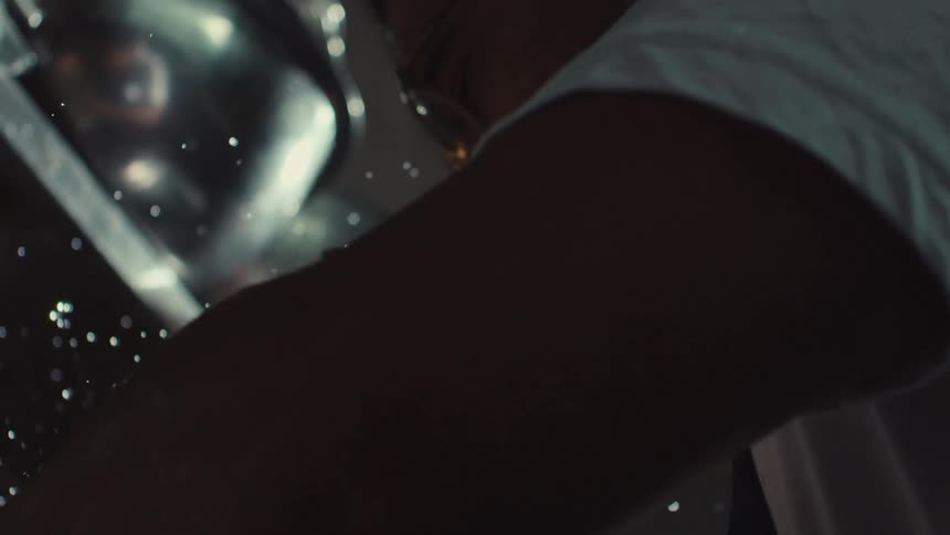 Dramatic low-angle slow motion shot of water droplets falling as a man leans over a sink