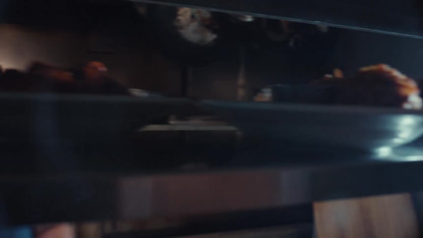 From the serving window, a chef places finished plates on the counter and rings the service bell