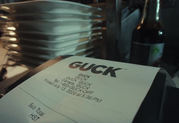 A close-up shot of a restaurant bill with stacks of white plates visible in the background