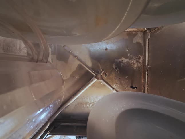 A rotating spray arm inside an industrial dishwasher cleans the interior before the light turns off
