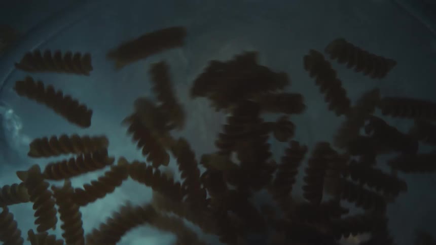 A worms-eye view of fusilli pasta boiling and swirling in a pot of hot water on the stove
