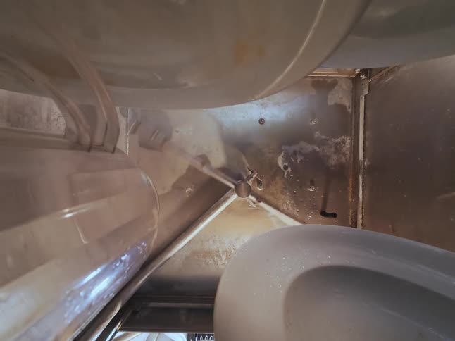 Top-down view of a spinning water nozzle spraying inside an industrial cleaning machine during a cycle