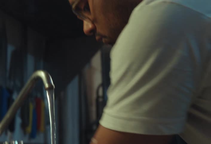 A male restaurant worker meticulously washes his hands and forearms with soap under running water in a stainless steel commercial sink