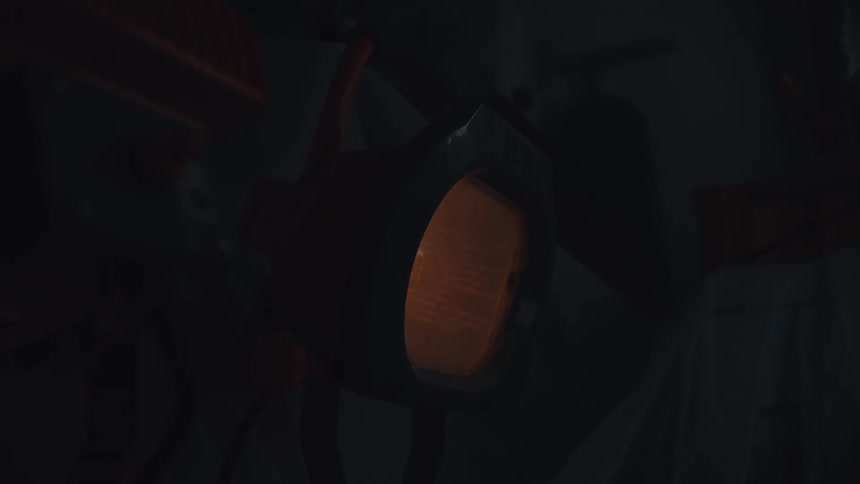A close-up shot of a bright orange industrial work light slowly fading to black in a workshop