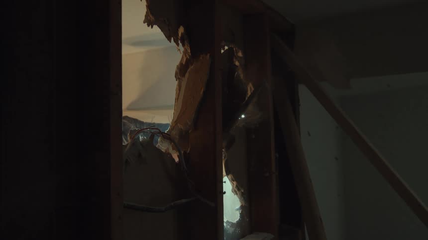 Slow motion shot through a broken wall of a sledgehammer demolishing drywall during a home renovation
