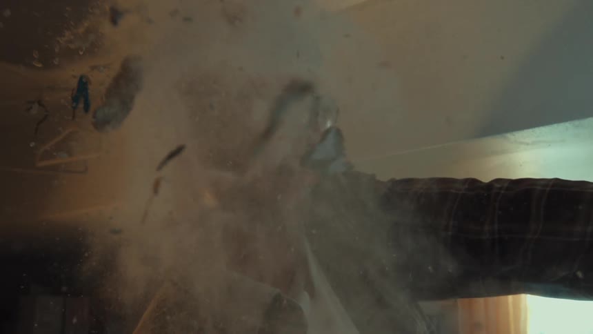 A man wearing safety glasses gets hit in the face by an explosion of white powder in super slow motion