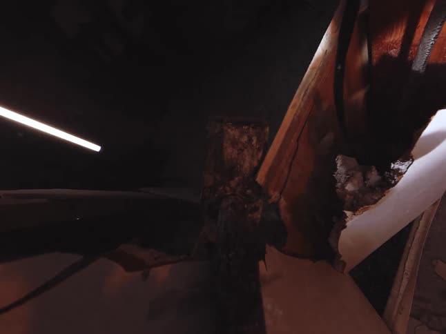 First-person point of view of a sledgehammer smashing through a wall in a dark and messy room