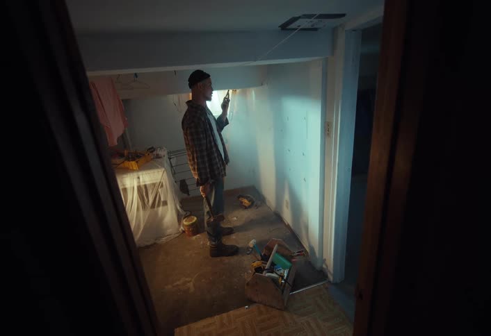 A determined man starts a demolition project, swinging a sledgehammer to break down a drywall in a dark basement