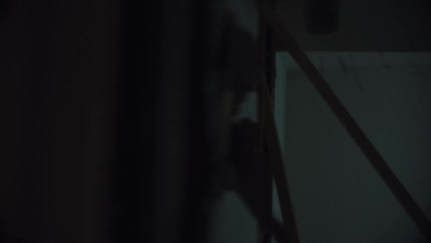 A man demolishes a wall with a sledgehammer in a dusty, backlit room during a home renovation