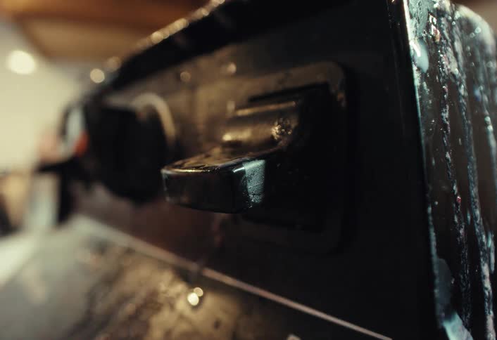 A finger flips a black plastic switch on a grimy piece of machinery in an extreme close-up shot