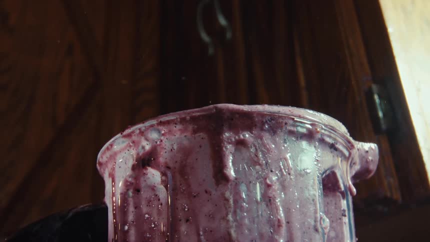 Super slow-motion close-up of a messy berry smoothie overflowing and splashing out of a blender
