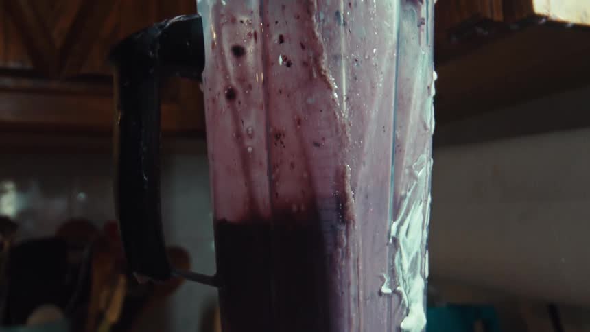 Super slow motion close-up of a messy, overfilled blender erupting with a purple fruit smoothie