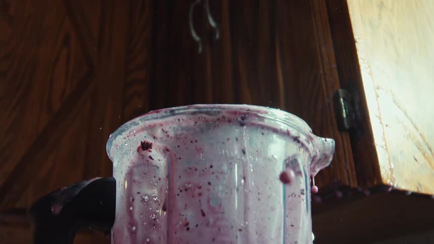 Slow motion close-up of a purple berry smoothie splashing out of an overflowing blender, creating a mess in the kitchen