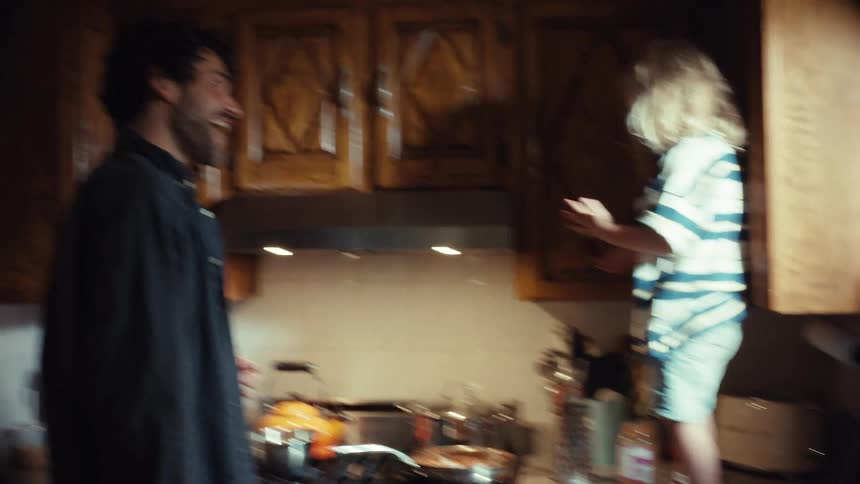 A happy father and his young son share a heartwarming moment cooking dinner together in their kitchen