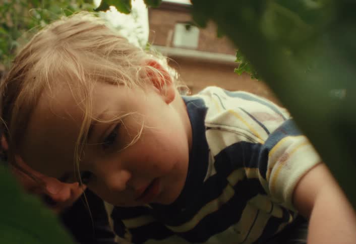 A curious father and his young son share a moment of discovery while exploring their lush backyard garden together