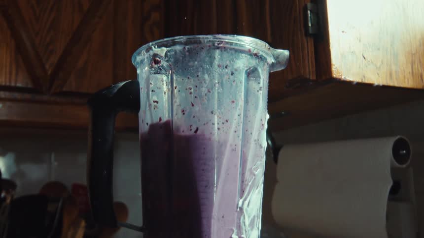 Super slow motion close-up of a messy purple smoothie overflowing and splashing out of a blender in the kitchen