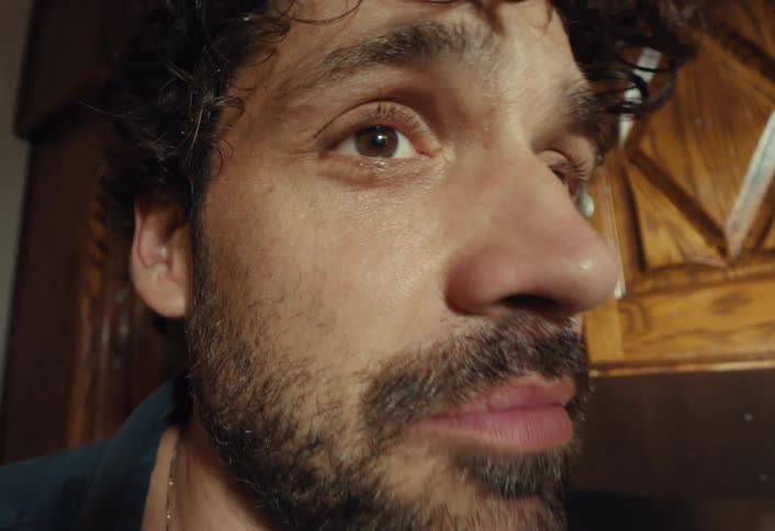 An extreme close-up of a man's face as he gets sprayed with liquid in slow motion