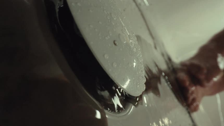 A person with dirty feet washes them in a bathtub as the water fills up in slow motion