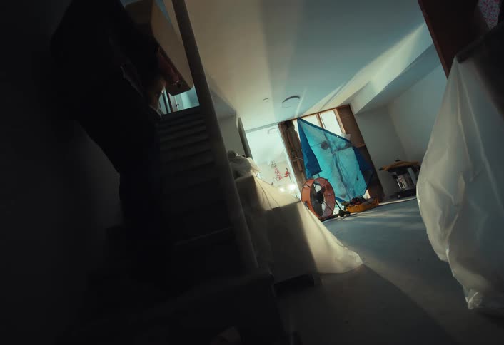 A man in slow motion carries heavy cardboard boxes up the stairs of his new home during a move