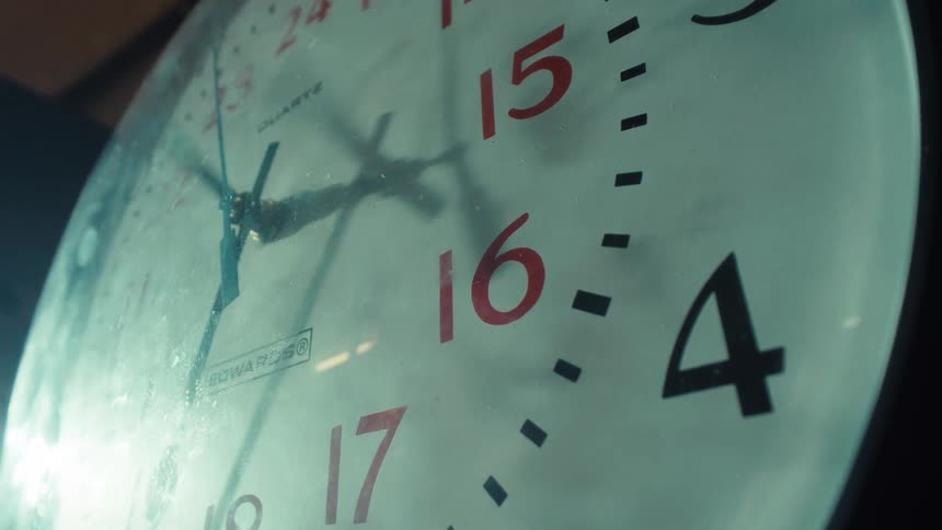 A dramatic time-lapse of the rapidly spinning hands on an old, dusty 24-hour wall clock