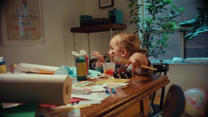 A playful toddler with paint on their face gets creative and messy during an arts and crafts session at home
