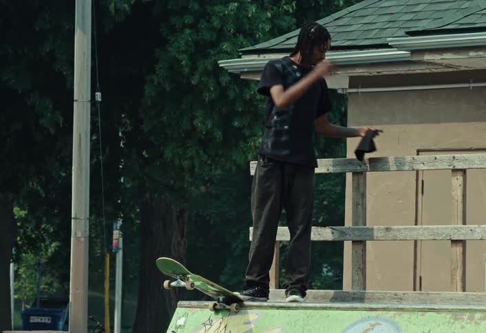 A male skateboarder takes off his beanie before dropping into a halfpipe at the skatepark