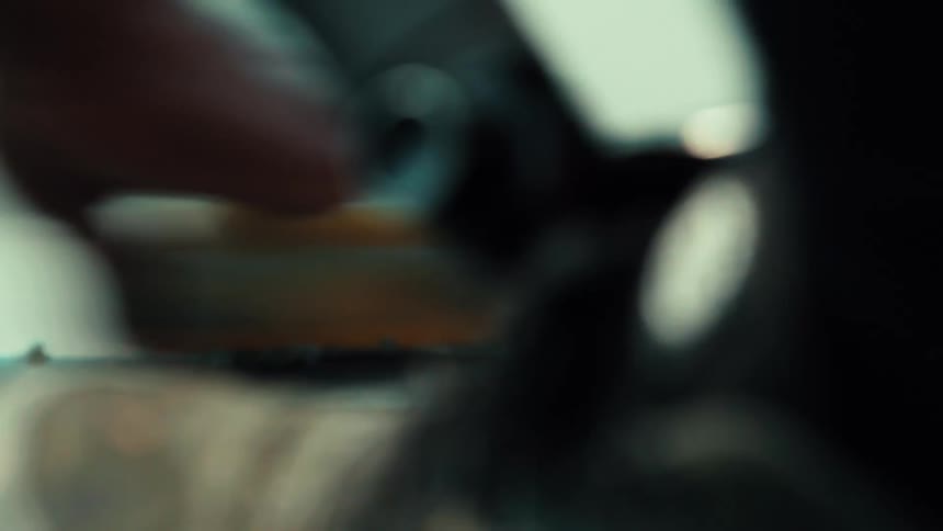 A close-up shot of a person's hands applying wax to a metal rail for skateboarding
