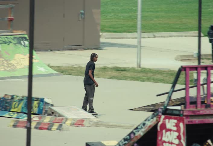 A skateboarder rides down a ramp and performs a trick over an obstacle at a colorful, graffiti-covered outdoor skatepark