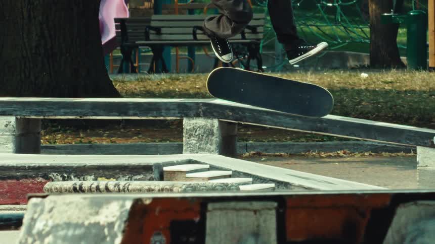 In an impressive super slow motion display, a skateboarder executes a kickflip to a boardslide grind down a ledge at an urban skatepark
