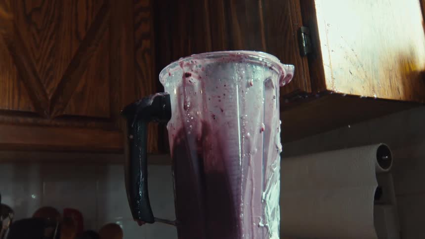 A purple fruit smoothie erupts from an overflowing blender, creating a huge mess in super slow motion
