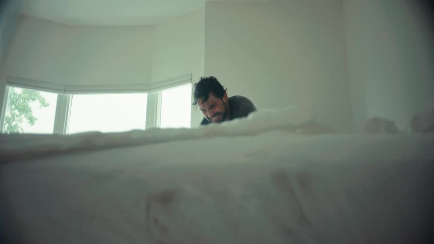 A camera pushes in from a hallway to find a father joyfully tickling his laughing child on a messy bed