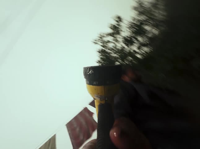 A chaotic first-person perspective of a person holding and spraying a garden hose nozzle in a backyard