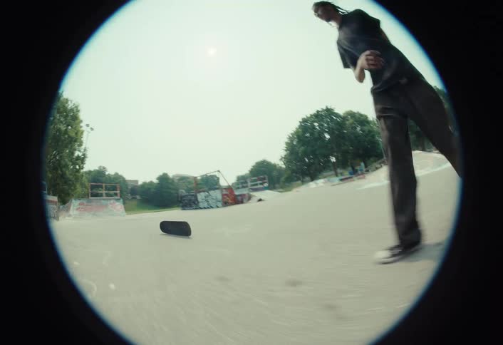 Fisheye shot of a skateboarder in slow motion failing a rail grind trick and then playfully running toward the camera