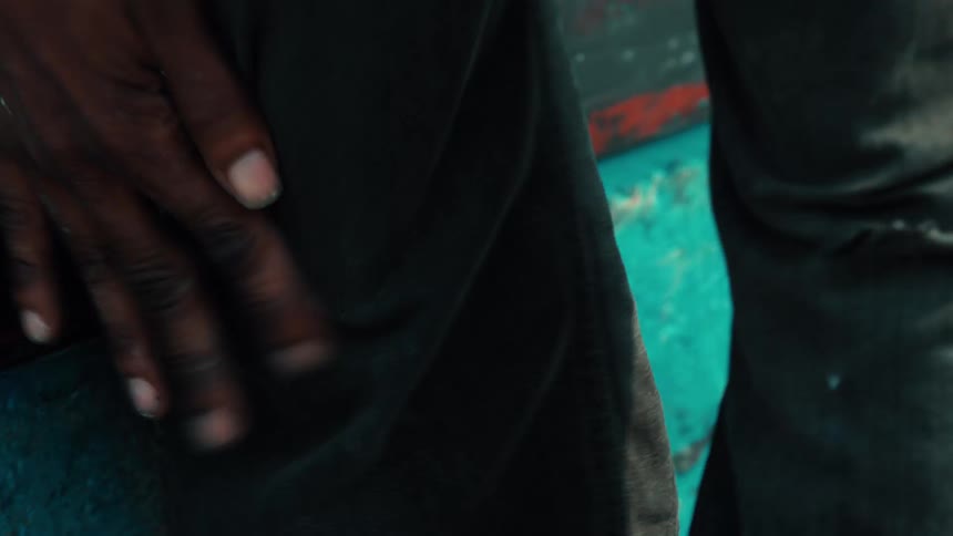 A close-up shot of a man rubbing his dirty hands together and wiping them on his pants