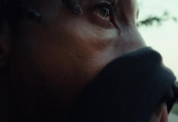 A powerful close-up shot captures a single tear streaming down the cheek of a distressed young Black man