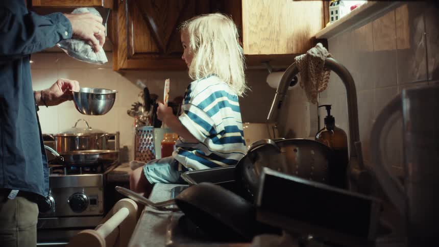A father and his young child spend quality time together preparing dinner in their cozy kitchen