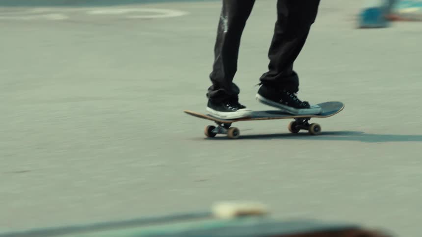 Slow motion side view of a young man skateboarding, grinding on a rail in a gritty, urban skatepark