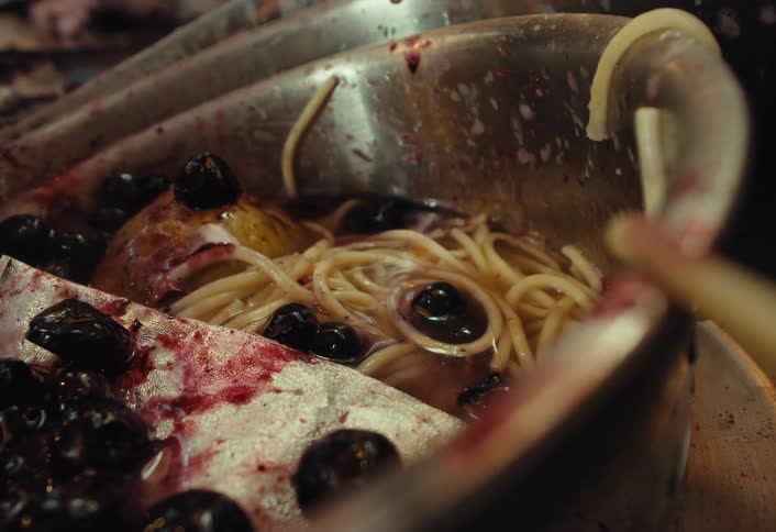 A disgusting close-up shot of food waste as berries are added to a dirty sink filled with old noodles and water