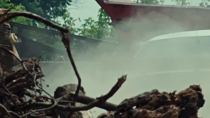 Slow motion shot of a paintball gun firing from a car window, enveloping the scene in a cloud of smoke