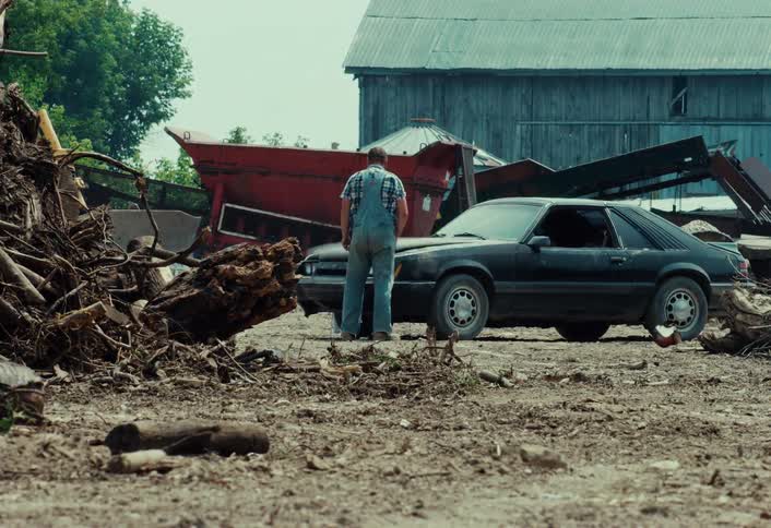 A frustrated farmer in overalls slams the hood of his smoking vintage muscle car and walks away defeated