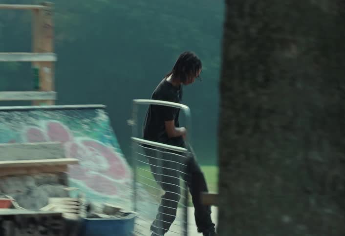 A stylish skateboarder cruises through a graffiti-covered urban skatepark in a smooth slow-motion tracking shot