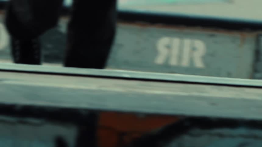 Cinematic slow-motion pan from a skateboarder's feet and board to a close-up of their face in a gritty skatepark