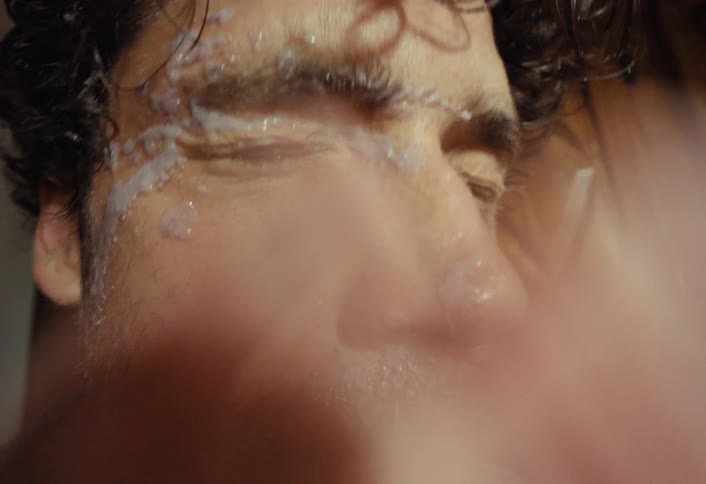 Extreme close-up slow-motion shot of a bearded man getting a smoothie splashed in his face