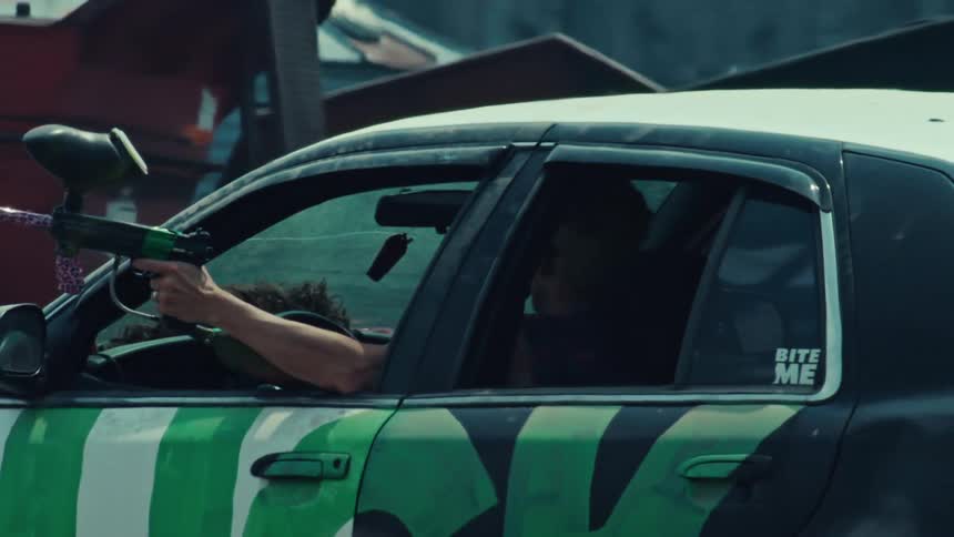 Close up of a paintball gun firing out of a car window in super slow motion