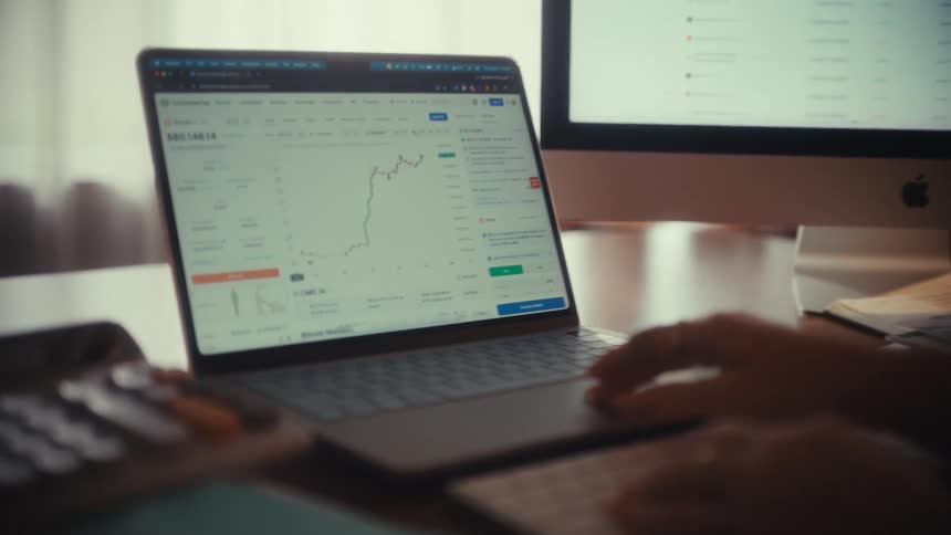 A financial analyst tracks cryptocurrency price movements on a laptop in their office, with the camera slowly zooming in on the chart