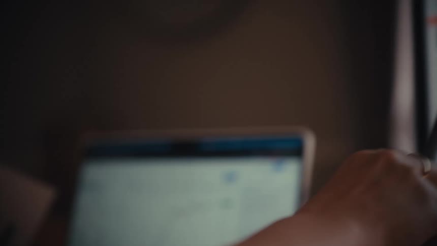 A financial analyst uses a stylus to trace a rising cryptocurrency chart on a laptop screen in a slow-motion close-up