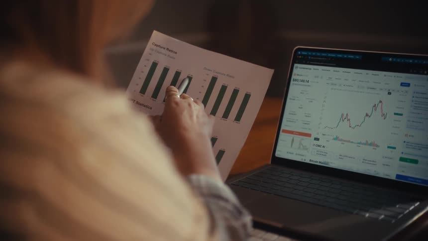 An investor meticulously analyzes financial data, comparing a rising line graph on a laptop with a printed bar chart