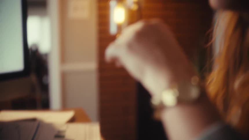 A focused woman types on her computer keyboard before the camera reveals her pleasant smile while working